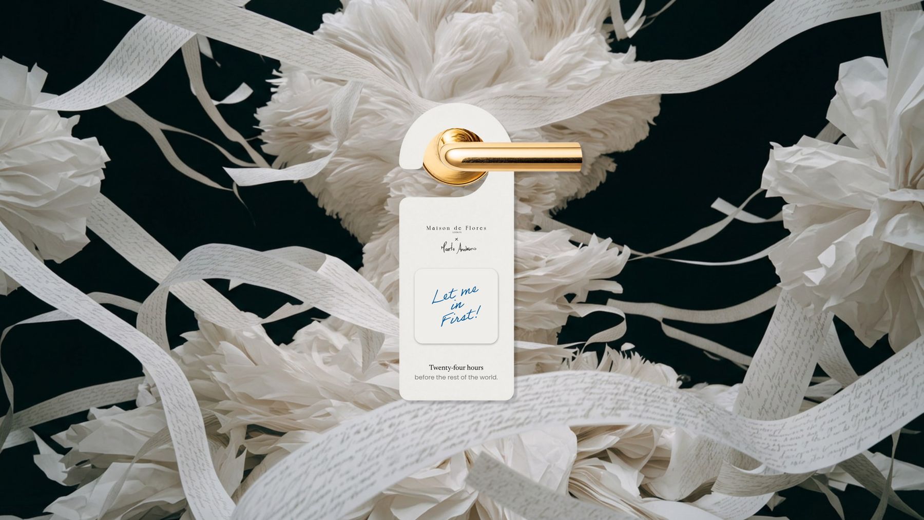 A door hanger reading Let me in first, on a brass handle among paper flowers